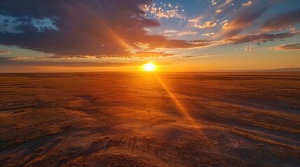 A breathtaking sunrise over a vast, open plain, with the sun rising over the horizon, casting a long shadow across the flat landscape