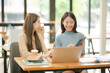 © aekachai - Two women work with tablets,  work and chatting about paperwork and graphs.