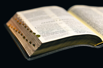 Open Bible on a black background. Religion concept.