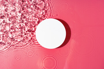 Poster - bright circular object floating on water with pink ripples in a serene setting during daylight