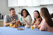 © Antonioguillem - Happy interracial roommates and friends talking at breakfast