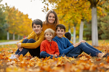 Wall Mural - Cute happy children, siblings, boys, playing with knitted toys in the park, autumntime