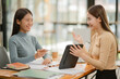 © aekachai - Two women work with tablets,  work and chatting about paperwork and graphs.