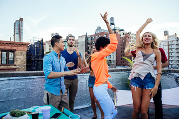 Group of friends spending time together on a rooftop in New york city, lifestyle concept with happy people