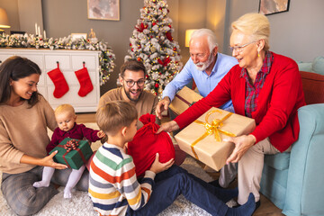 Happy multi-generation family exchanging Christmas presents at home