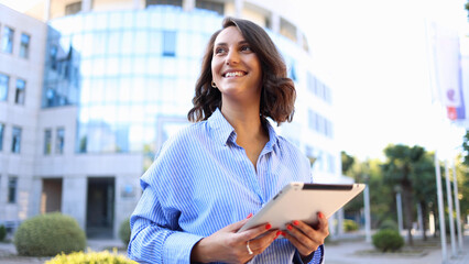 beautiful, young businesswoman using a digital tablet and enjoying in the city