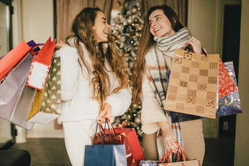 Two young women enjoying Christmas shopping on a decorated street.