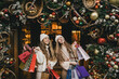 © polinaloves - Two young women enjoying Christmas shopping on a decorated street.
