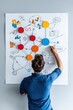 © CHA - A person engages in brainstorming and planning with colorful charts and diagrams on a wall, showcasing creativity and teamwork in an office environment.
