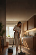 © Jose Luis Stephens - A woman is engaged in cleaning her kitchen with a vacuum cleaner, showcasing a tidy and well-lit space