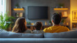 © Vitalii - back view of family watching movie on tv in living room at home
