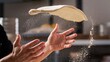 © hobonski - Close-up image of a person's hands tossing and stretching pizza dough, with a cloud of white flour dust suspended in the air around the dough.