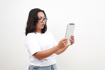 Portrait of asian business woman looking at digital tablet with surprised, shocked face, side view. Isolated on white