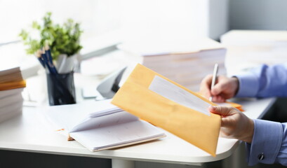 Close-up of man give yellow envelope to courier for further delivery to personal address. Write address on packages. Delivery service, transfer concept