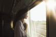 © dimedrol68 - Young woman riding a train and looking out the window.