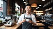 © Arceli - joyful young asian barista in a cafe holding cup