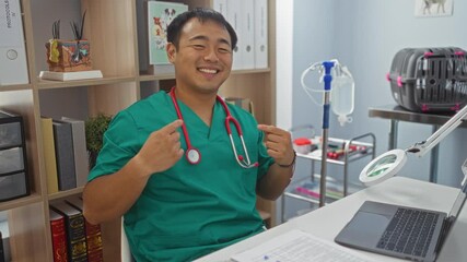 Canvas Print - Young chinese man in doctor uniform using laptop and pointing with happy smiling face and hand at veterinary clinic