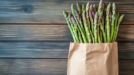 Eco friendly paper bag filled with freshly harvested organic purple and green asparagus spears set against a wooden backdrop