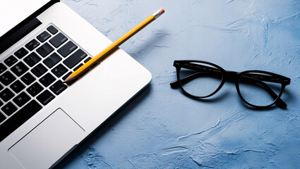 laptop keyboard and pencil and glasses, office desk table with blank notebook, computer, supplies. Top view with copy space. Flat lay.