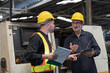 © amorn - Two male engineer checking, repair, maintenance CNC machine in factory. Group of male technician working with CNC machine during manufacturing process