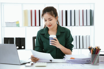 Confident Asian businesswoman in her office checking financial reports on her laptop. Analyzing data, planning strategies and full of success, professionalism and entrepreneurial spirit.