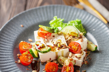 Wall Mural - Feta cheese in cubes and vegetables - tomatoes and cucumbers in a plate. Light Greek salad with seedlings