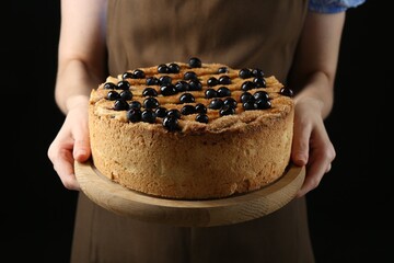 Poster - Woman with delicious homemade blueberry pie on black background, closeup