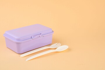 Sticker - Plastic lunch box with cutlery on peach background. Space for text