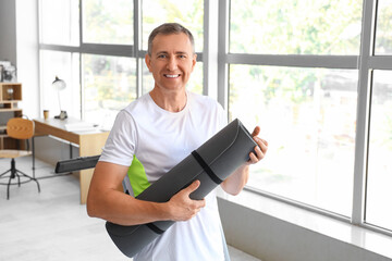 Poster - Sporty mature man with fitness mat at home