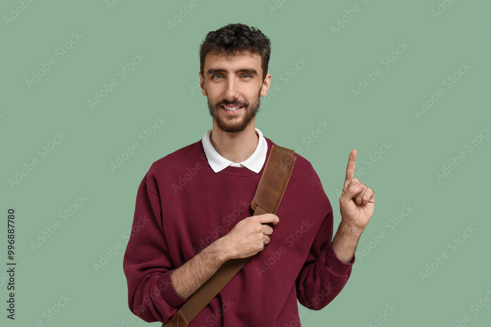 Male student pointing at something on green background