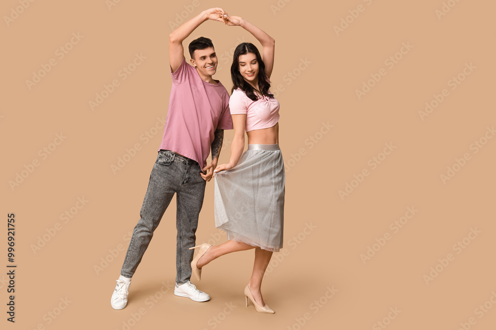 Happy young couple dancing on brown background