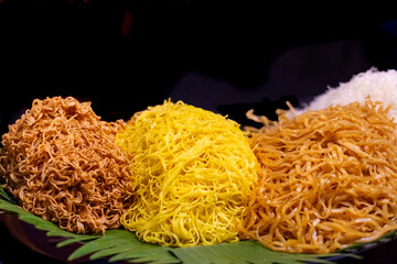 Various types of prepared noodles on table in stall at street market, black background