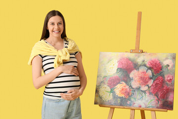 Canvas Print - Beautiful female pregnant artist painting on canvas on yellow background