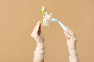 Wall Mural - Female hands in laced gloves with vibrator and flower on color background, closeup