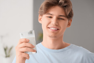 Poster - Young man with glass of milk at home, closeup