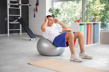 Canvas Print - Sporty young man training on fitball in gym