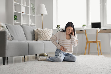 Canvas Print - Young woman with severe abdominal pain calling an ambulance at home