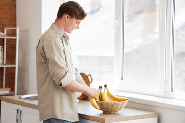 Sticker - Young man taking banana from bowl in kitchen