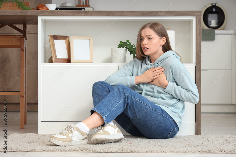 Young woman having panic attack on floor in kitchen