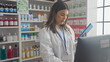 © Krakenimages.com - A focused woman pharmacist reviews inventory on a tablet inside a well-stocked pharmacy