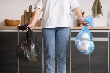 Canvas Print - Woman with full garbage bags in kitchen