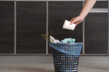 Canvas Print - Woman throwing garbage into trash bin in kitchen