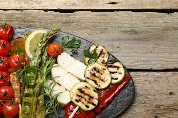 Delicious grilled vegetables and cut chicken meat on wooden table, top view. Space for text