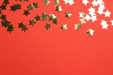 Wall Mural - Shiny confetti on red background, flat lay. Space for text