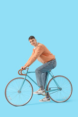 Poster - Young man in sneakers with bicycle on blue background