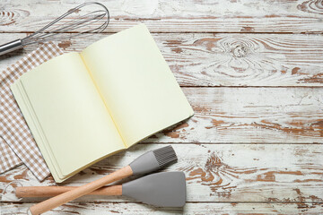 Canvas Print - Blank recipe book, kitchen utensils and napkin on light wooden background