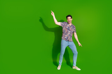 Poster - Full size photo of carefree good mood guy dressed print shirt jeans dancing on party raising finger up isolated on green color background