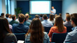 © cabado - Modern conference room filled with attentive diverse audience listening focused on blurred professional speaker presenter man or college teacher presenting with projection screen in distance at front.