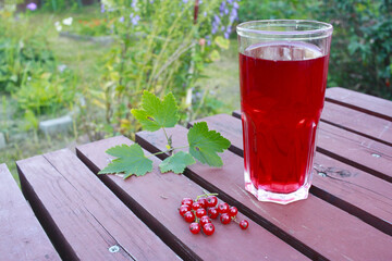 Red currant juice. Glass with red juice on the table