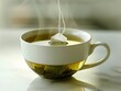 © Pat J. - A steaming cup of green tea with a tea bag string hanging out on a white background